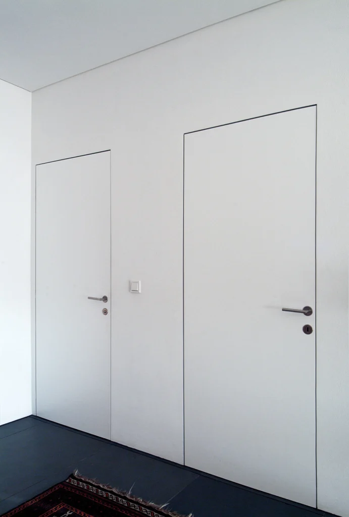 Moderne weiße wandbündige Türen ohne sichtbare Zarge im minimalistischen Interior